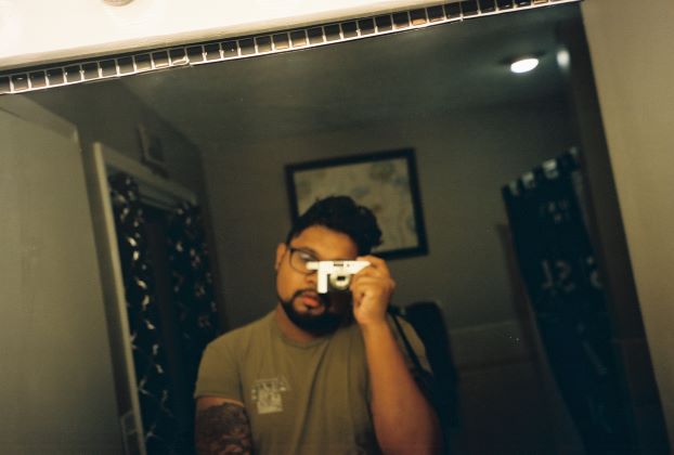 brown boy with film camera takes mirror picture